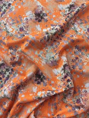 Orange fabric with watercolor splashes in brown, purple, and white.