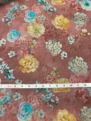Floral patterned fabric with peonies/roses of white, yellow, and blue  on a pinkish-brown background with a ruler for scale.
