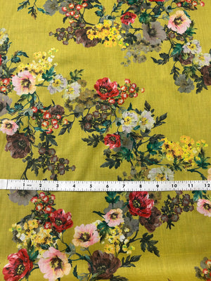 This is a cotton voile with a vibrant and unsaturated floral print of yellow, pink and red flowers on yellow background. with a ruler for scale on a yellow background