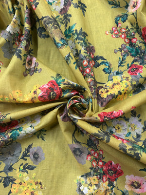This is a cotton voile with a vibrant and unsaturated floral print of yellow, pink and red flowers on yellow background.