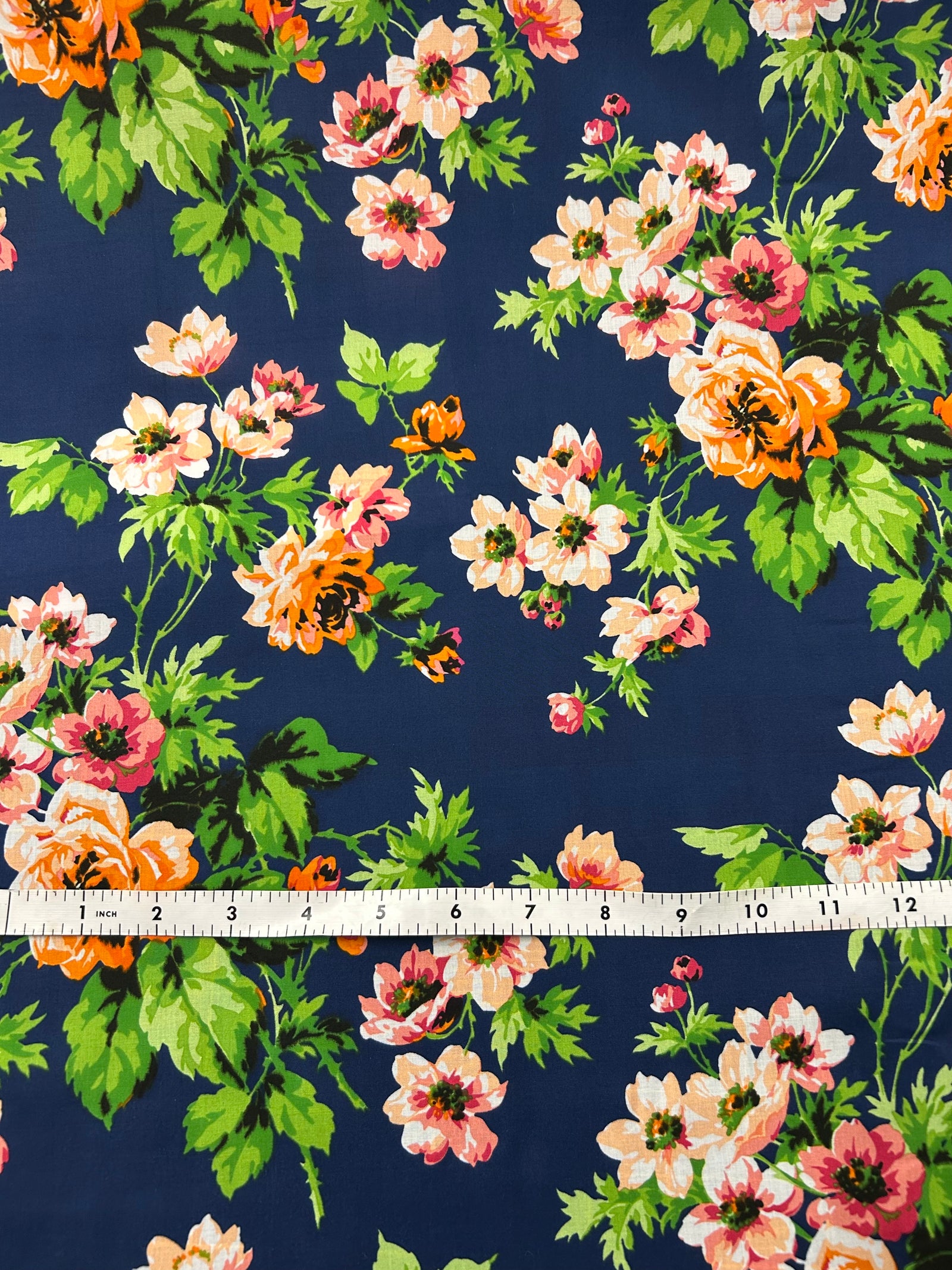 Floral pattern on fabric with pink, orange, and green flowers on a navy background