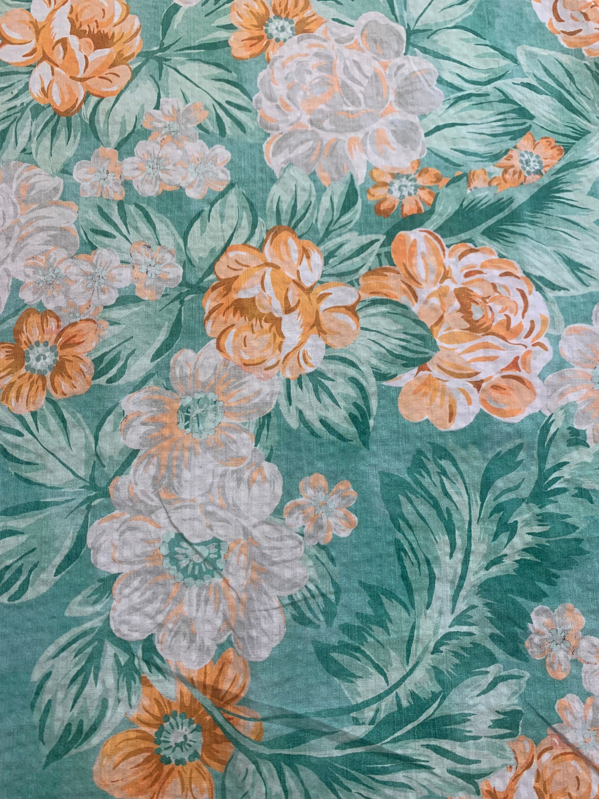 close up of a summery flat cotton seersucker with a muted orange and green tropical print
