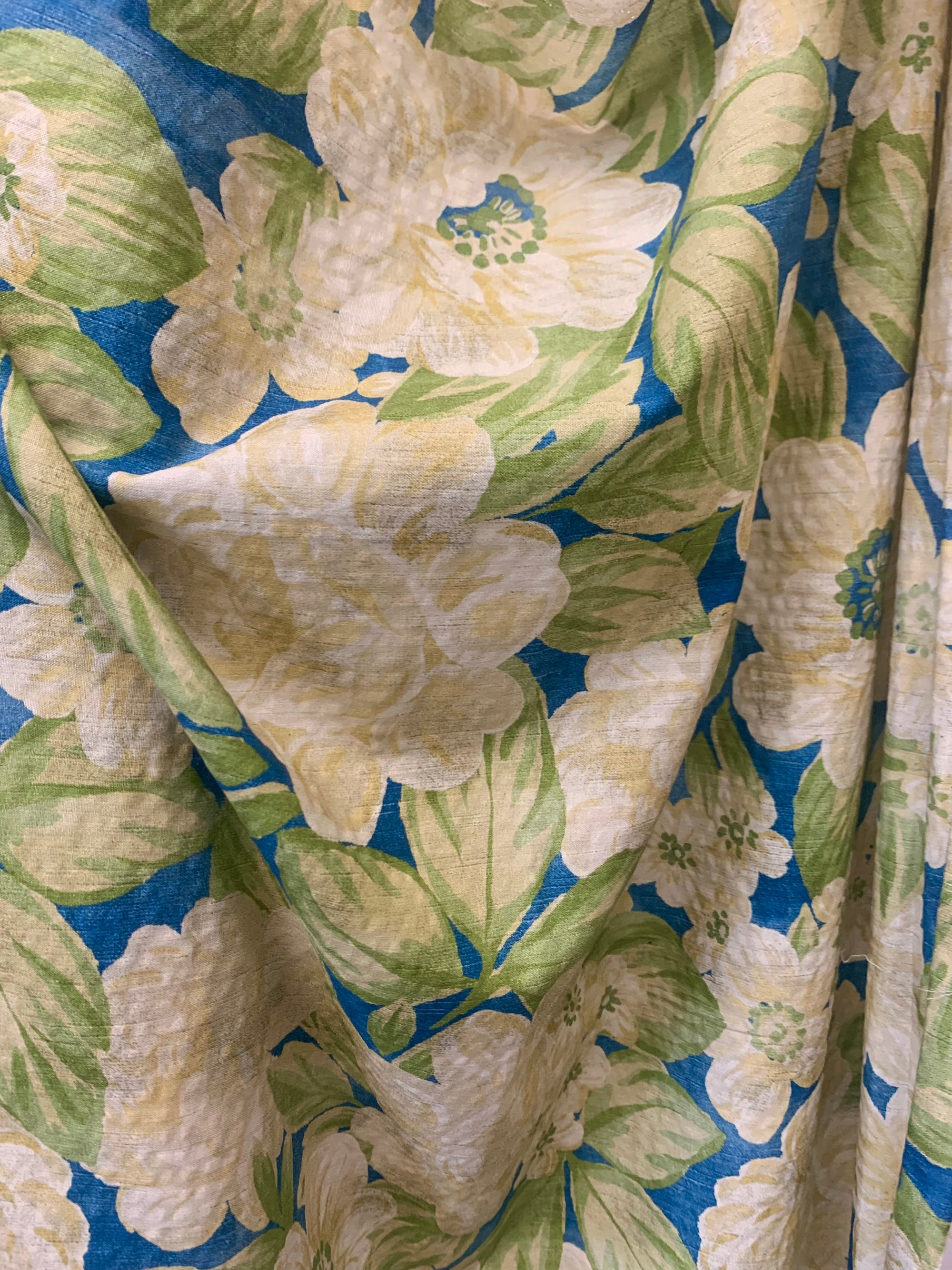 close up of flat cotton seersucker in a royal blue with a beige and green rose floral print