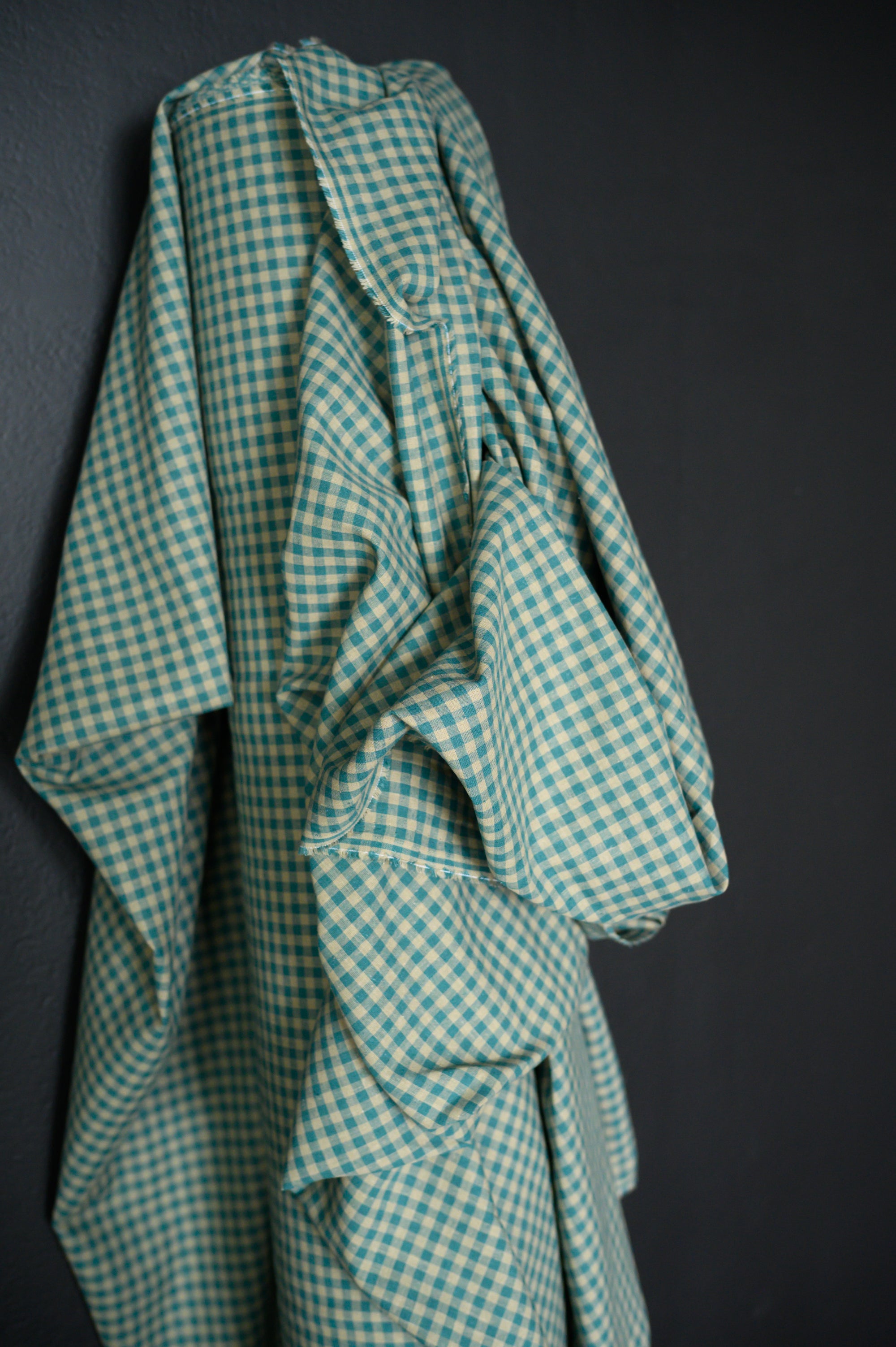 A roll of Teal and tan gingham, cotton/linen blend on a dark grey background.