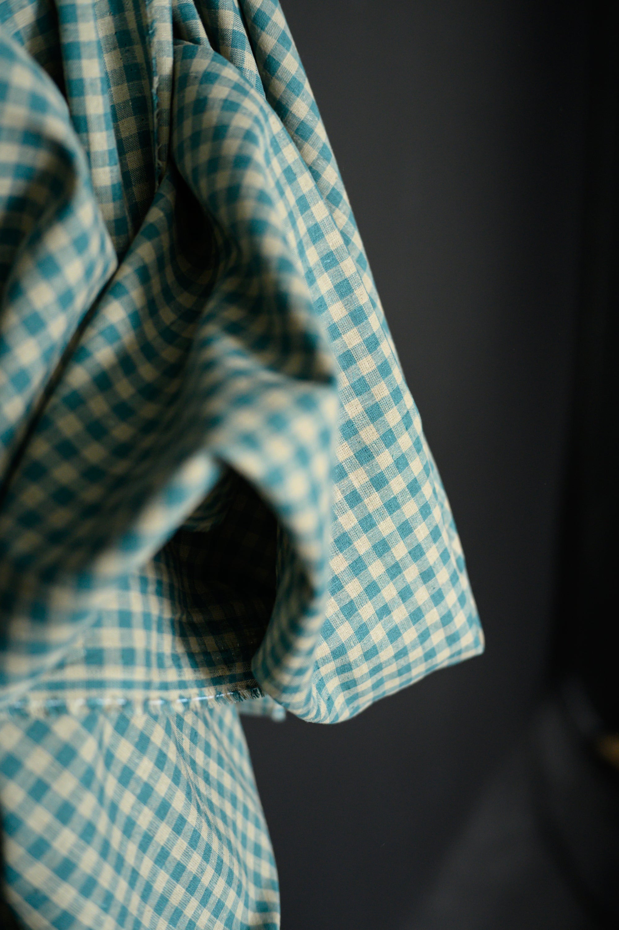 A roll of Teal and tan gingham, cotton/linen blend on a dark grey background.