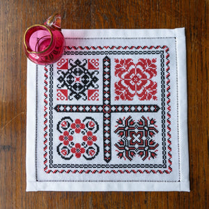 Embroidered placemat with floral patterns on a wooden surface