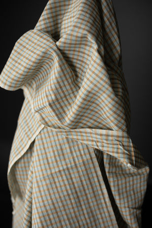 Fabric in a pale blue and pale orange plaid with a very dark grey background.