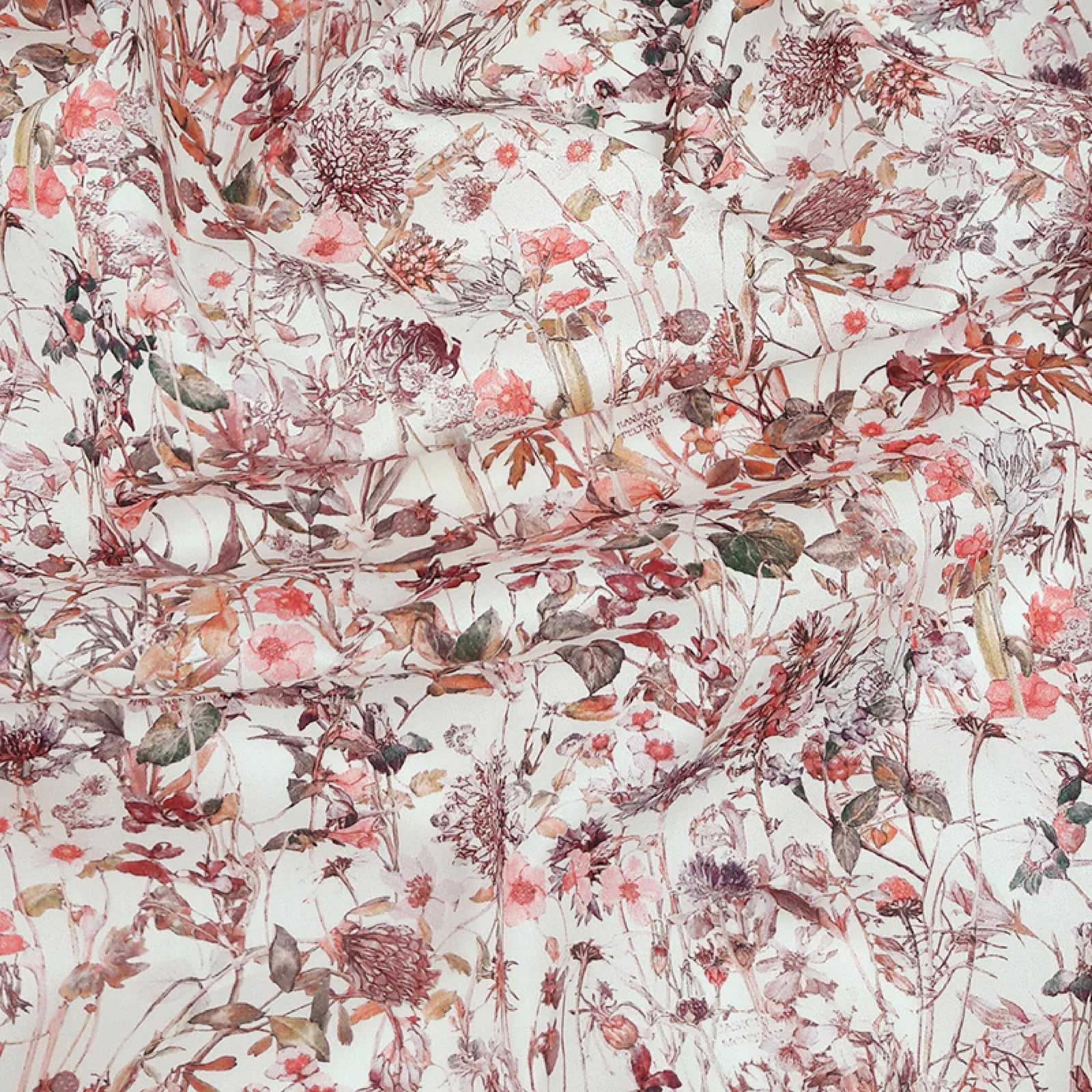 Cotton fabric with a vintage print with muted wild flowers in pinks and purples from Britain's landscape. On a white background.