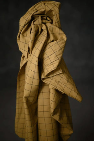 A greeny tan and black windowpane check fabric on a dark grey background