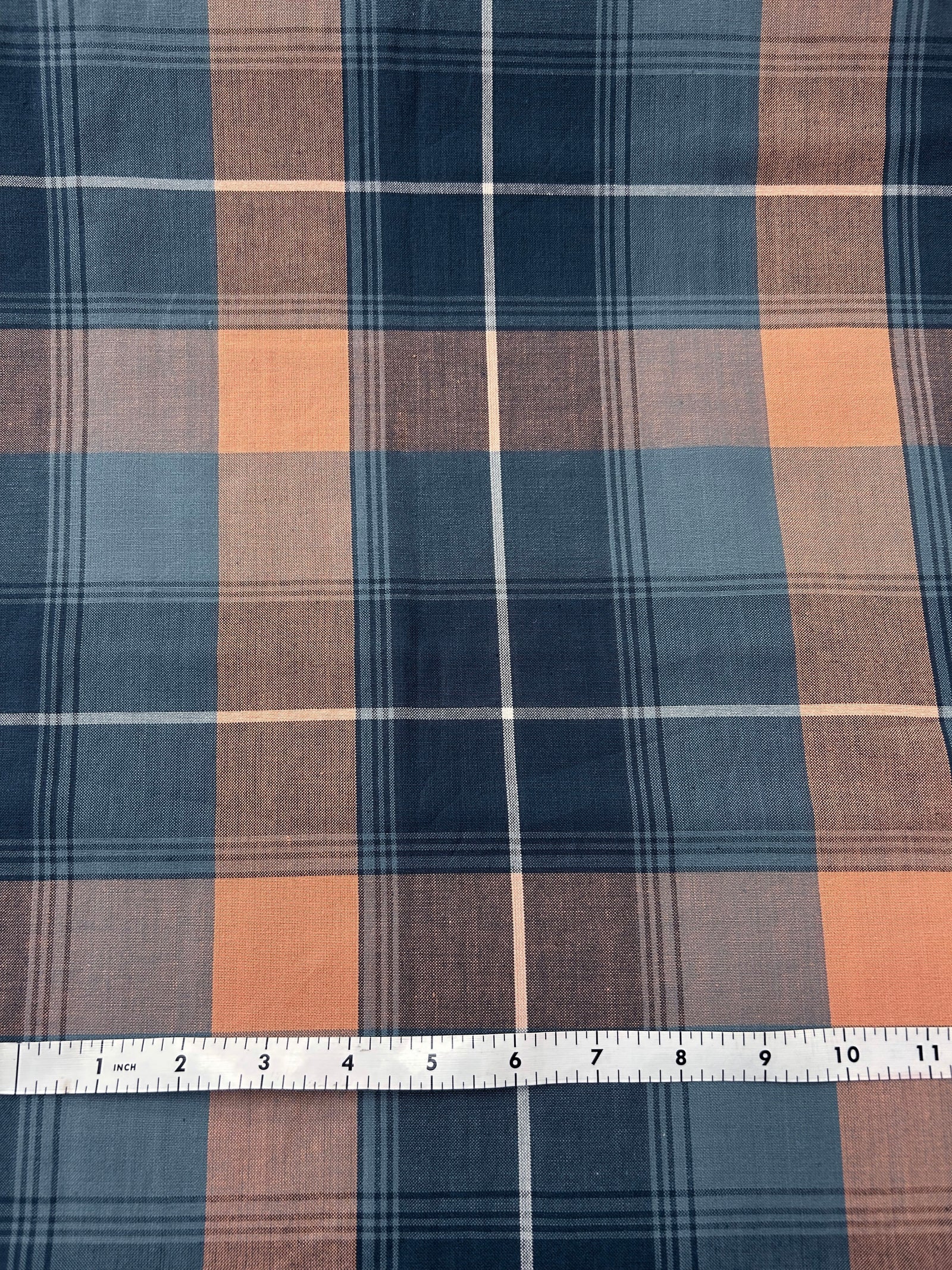 Plaid fabric with blue, and orange colors on a white background.
