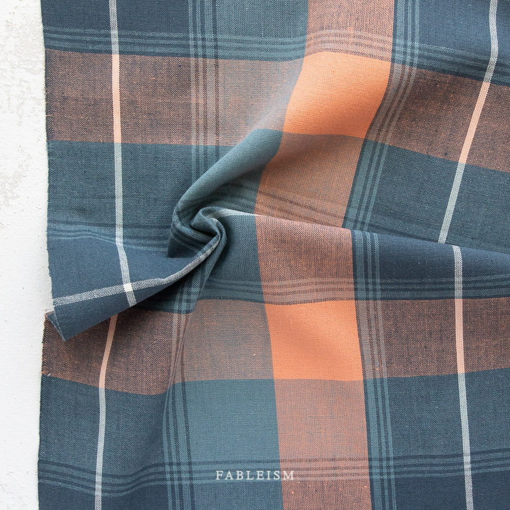 Plaid fabric with blue, and orange colors on a white background.