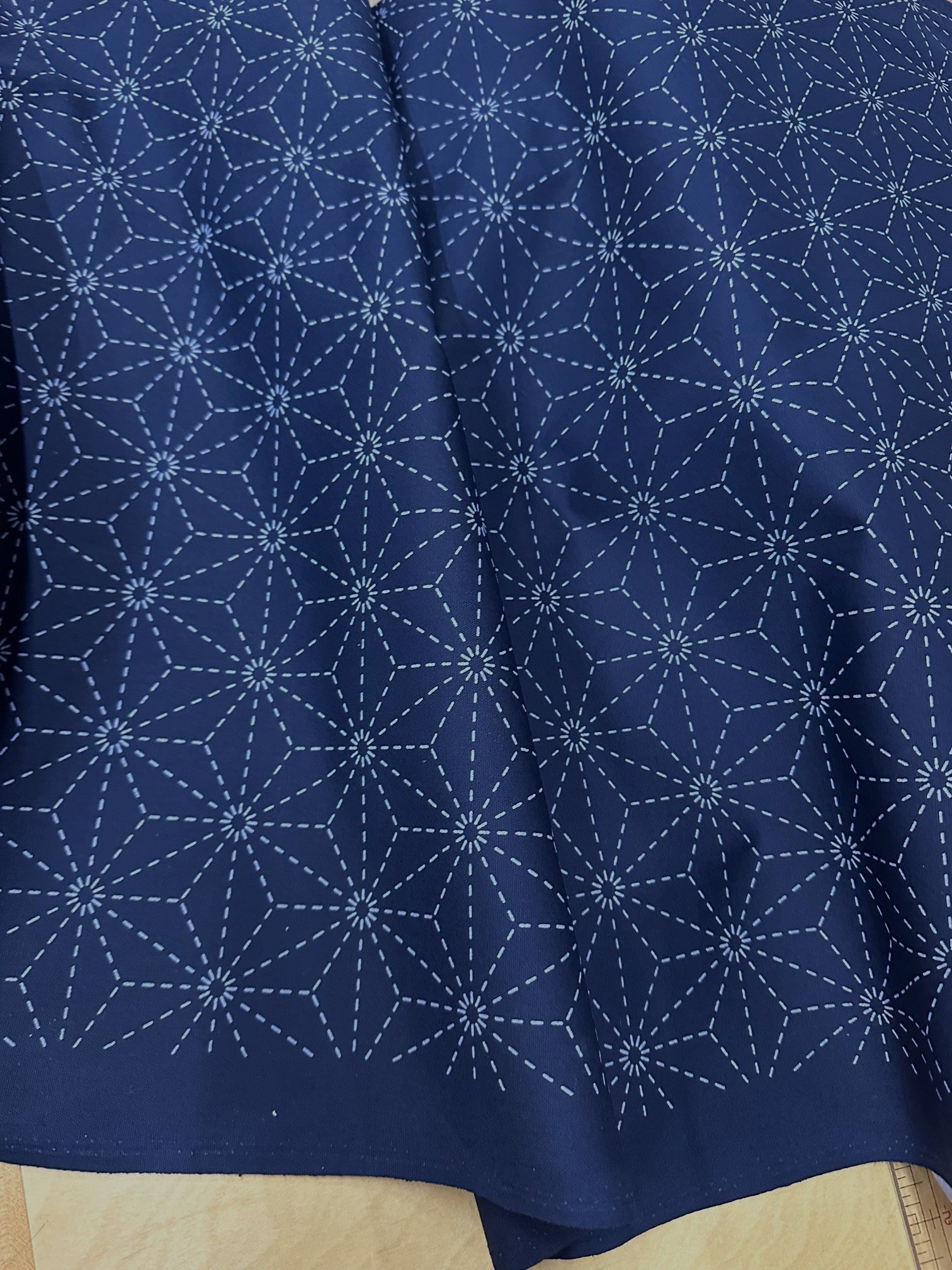 Navy blue fabric with white sashiko pattern on a beige surface