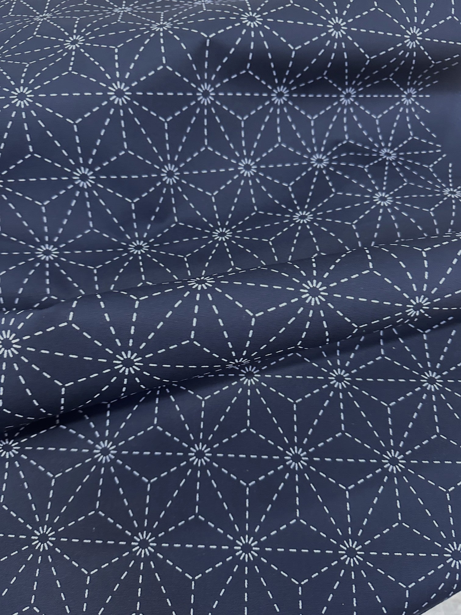 Navy blue fabric with white sashiko pattern on a beige surface
