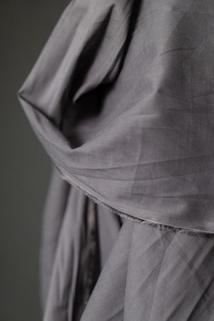 close up of roll of powdered grey fabric on a dark grey background