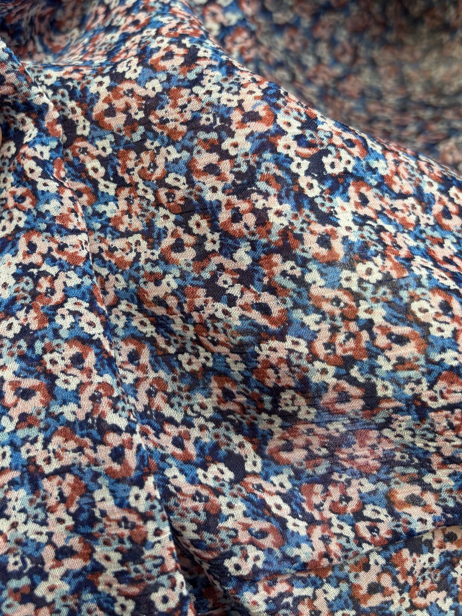 Close-up of a patterned fabric with blue, red, and beige colors.