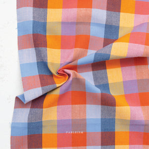 A colorful100% cotton fabric in a bold, woven check pattern in warm oranges, corals, yellows, soft pinks, and cool blues, on a white background.