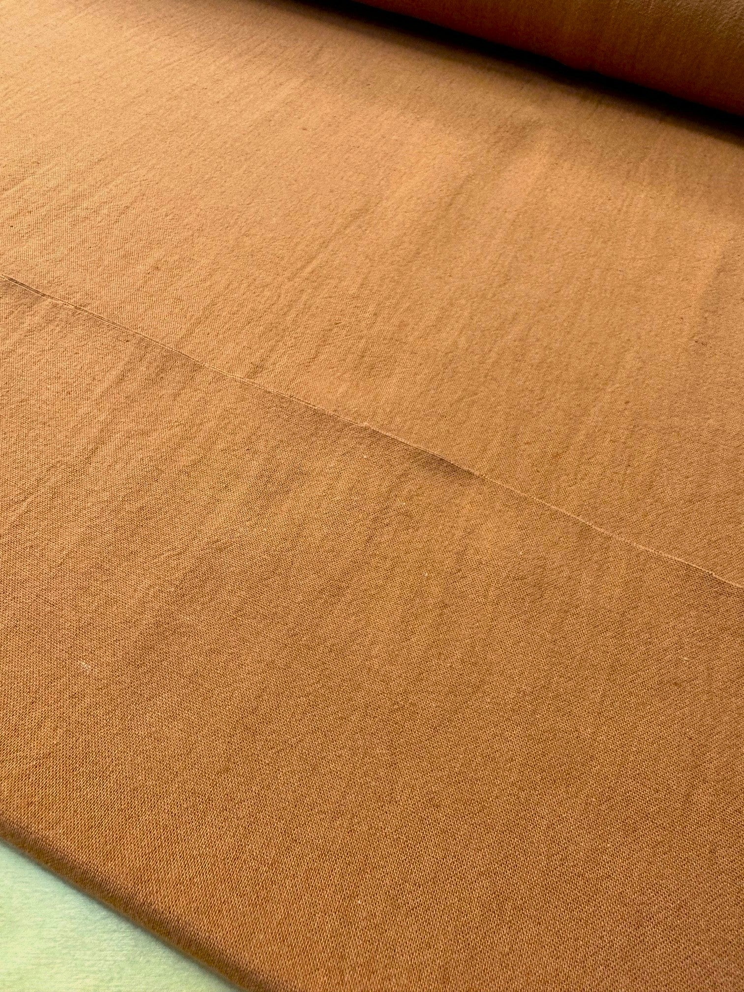 section of burnt orange colored cotton/linen fabric on a table