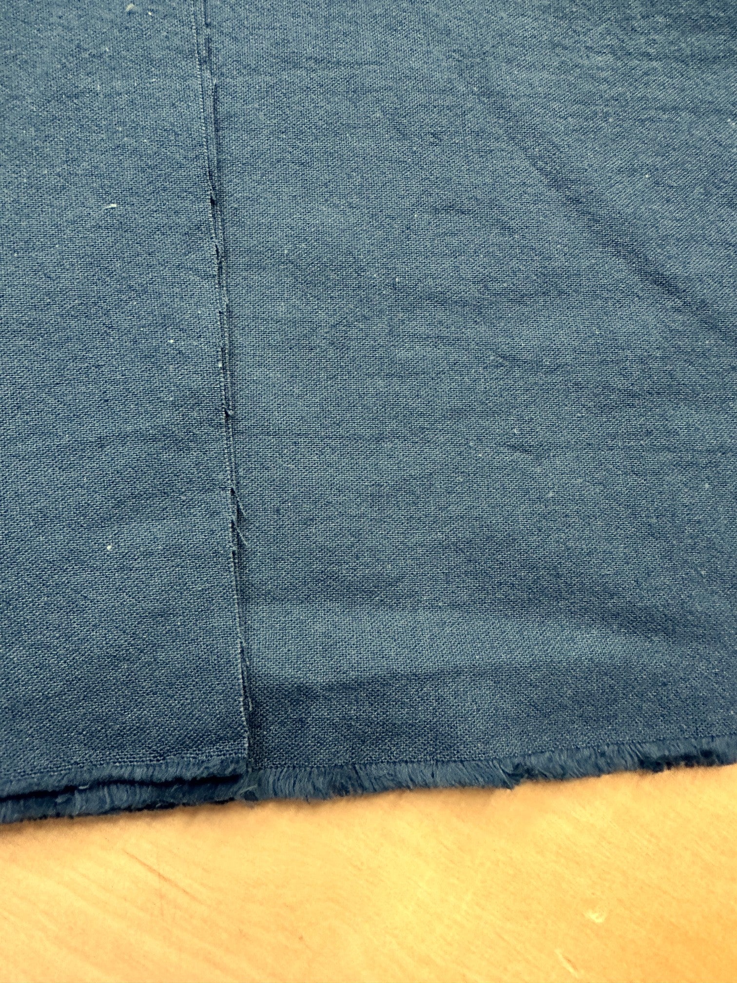 section of dark teal cotton/linen fabric on a wooden table