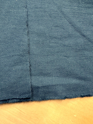 section of dark teal cotton/linen fabric on a wooden table