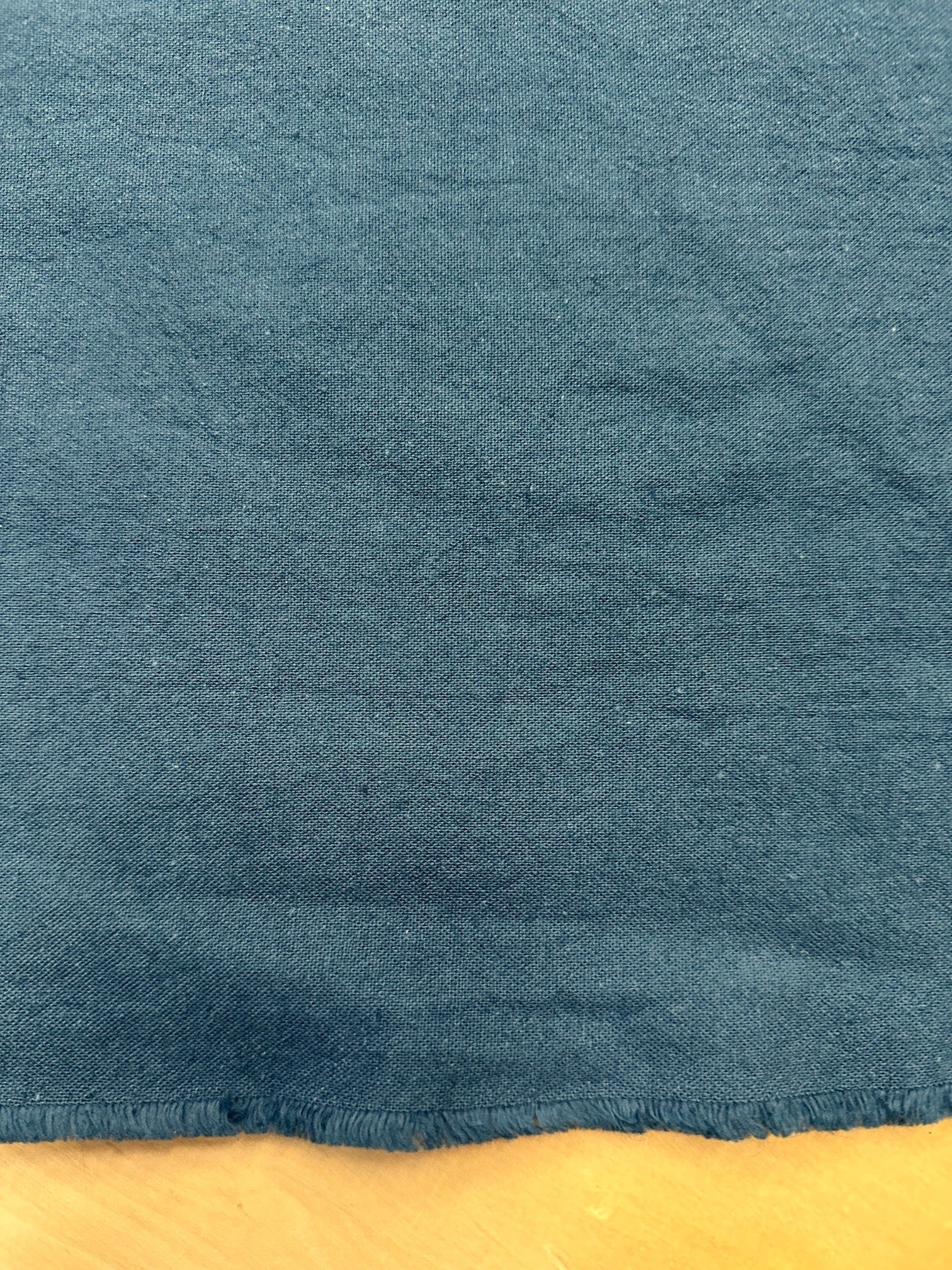 section of dark teal cotton/linen fabric on a wooden table