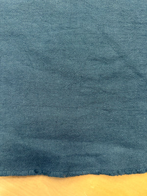 section of dark teal cotton/linen fabric on a wooden table