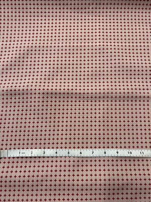 Fabric with a small star pattern and a ruler for scale on a pink background