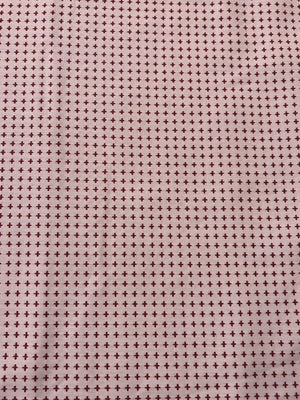 Patterned fabric with small crosses on a pink background