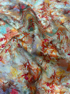 cotton lawn in a floral print with orange foliage and yellow, red, and blue paint brush strokes.