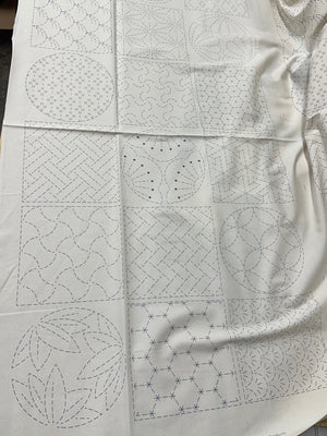 cream colored fabric with sashiko design squares printed on it.
