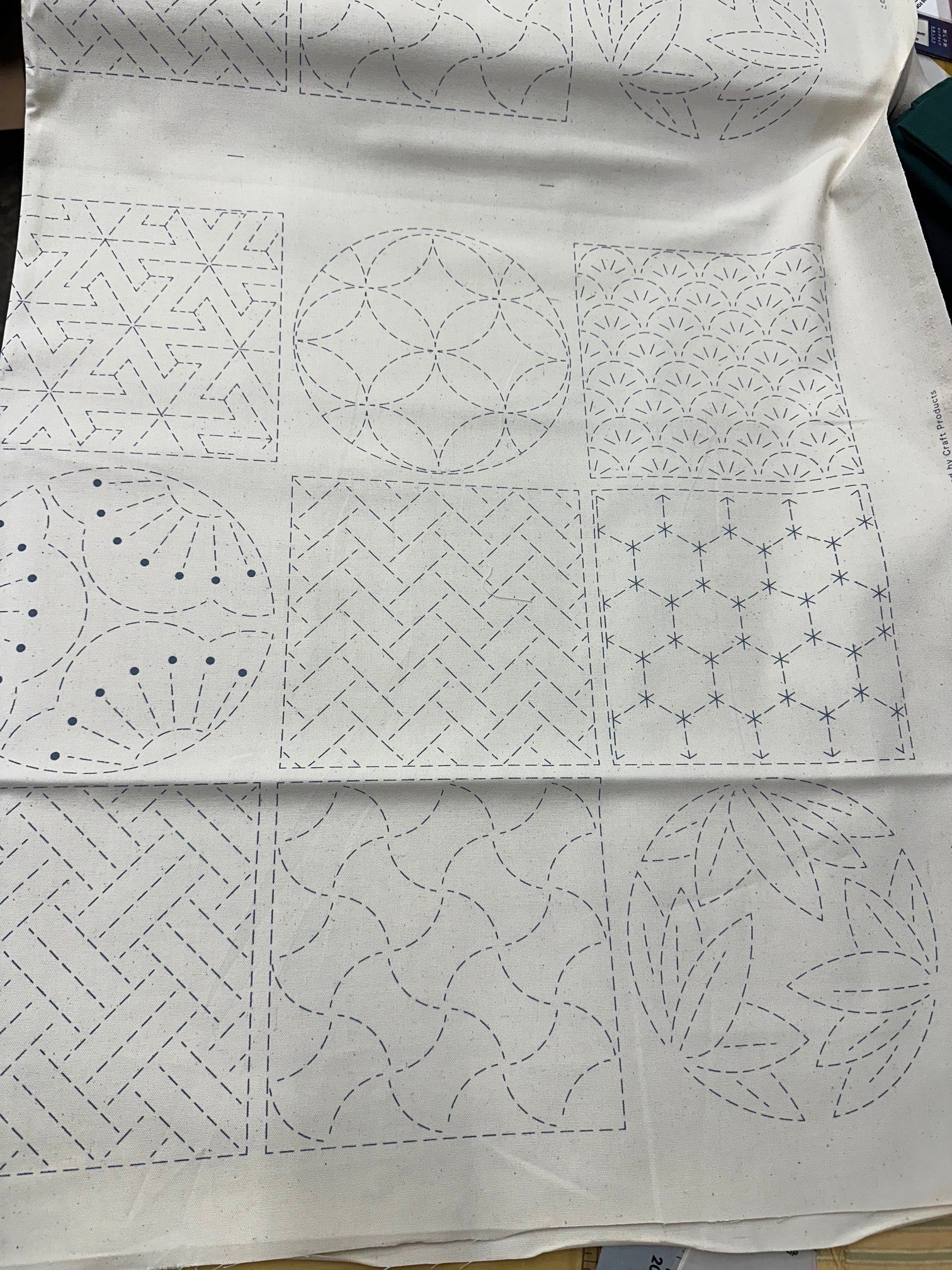 cream colored fabric with sashiko design squares printed on it.