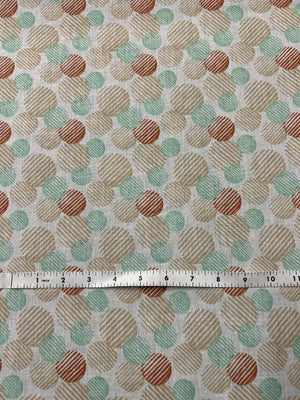 Linen fabric with a a retro abstract polka dot print fabric in mint, beige, and rust on an ivory background. The circles vary in size and are filled with fine diagonal stripe textures, creating a layered geometric look with a hand-printed feel and a ruler for scale