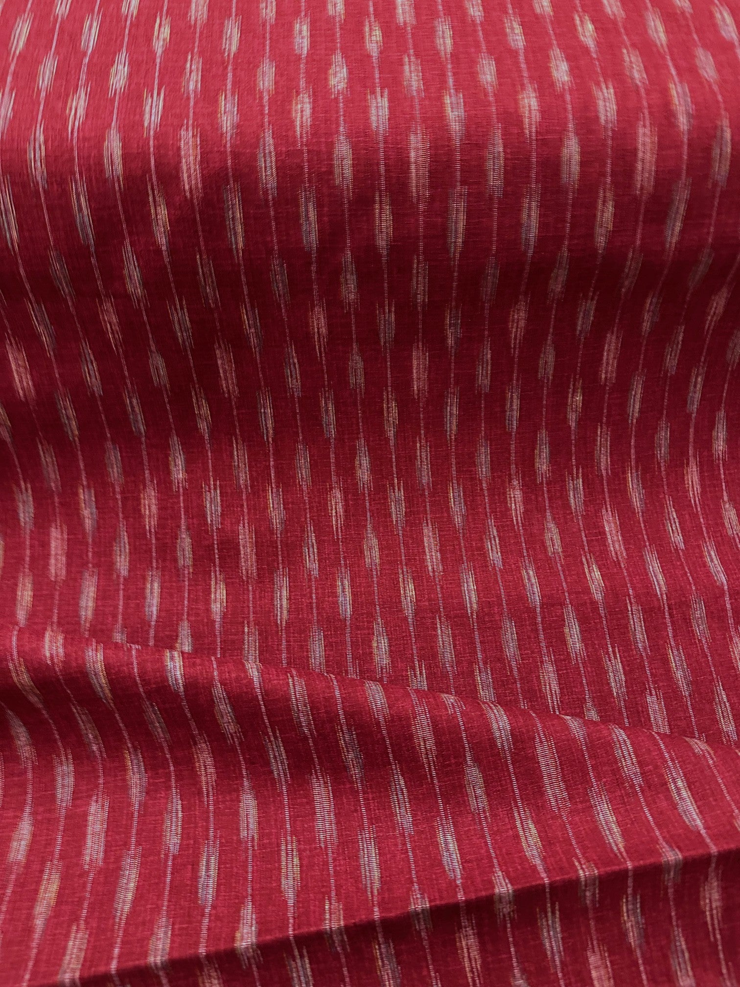 Textured red fabric with a pattern of small, evenly spaced lines 