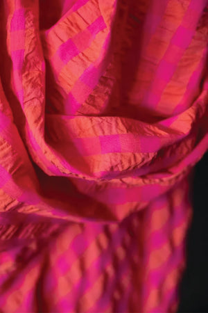 Close up of  summery bouncy cotton seersucker in a bright combination of fuchsia and orange.