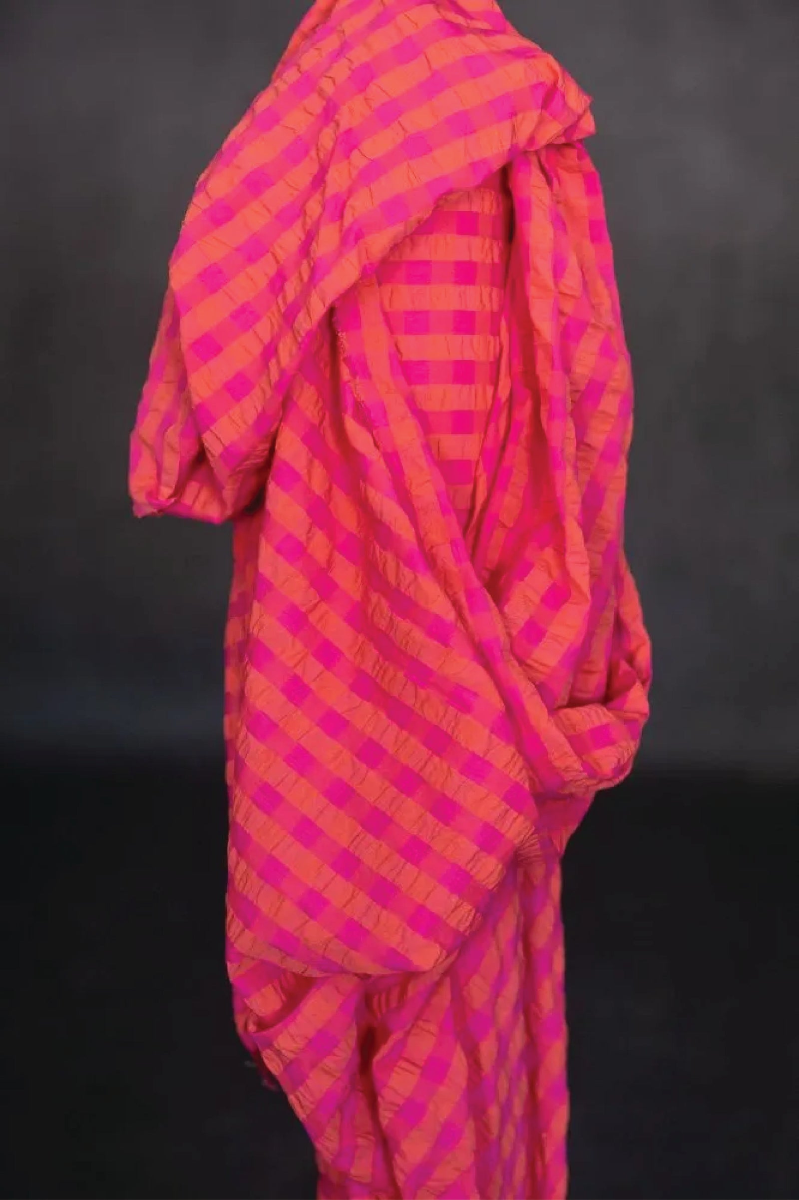 Close up of  summery bouncy cotton seersucker in a bright combination of fuchsia and orange.