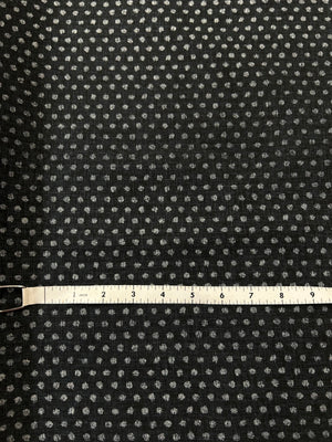 Black fabric with small white floral pattern and a measuring tape for scale.
