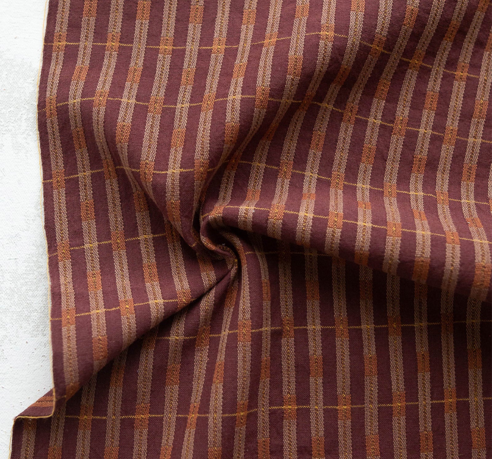 Close-up of checkered fabric with red, brown and beige pattern on a white background