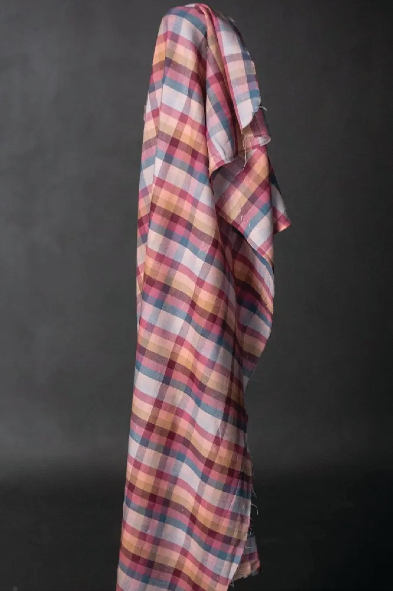 A cotton check fabric in berry tones on a dark grey background.