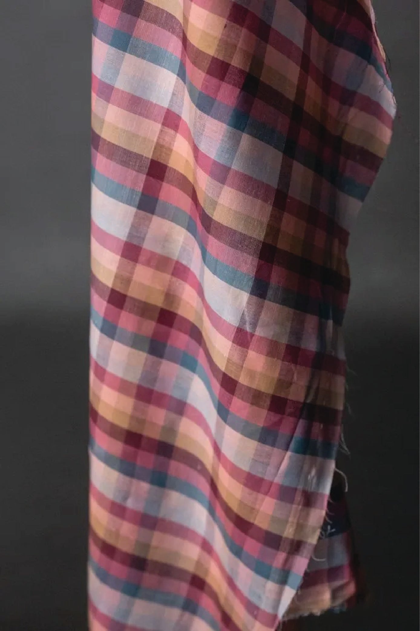 A cotton check fabric in berry tones on a dark grey background.