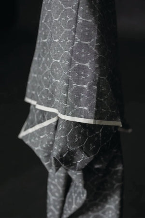 The warp and weft of this ikat is in black and white threads which results in a soft grey colour with a white geometric pattern. On a dark grey background