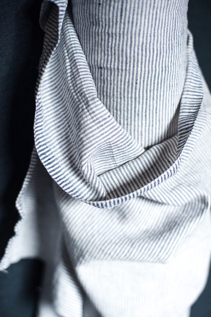 close up of a roll of fabric with navy blue and white skinny stripes going vertically on a navy blue background.