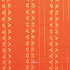 100% cotton fabric in a vibrant stunning orange color with a cream woven textured floral motif arranged in vertical rows.