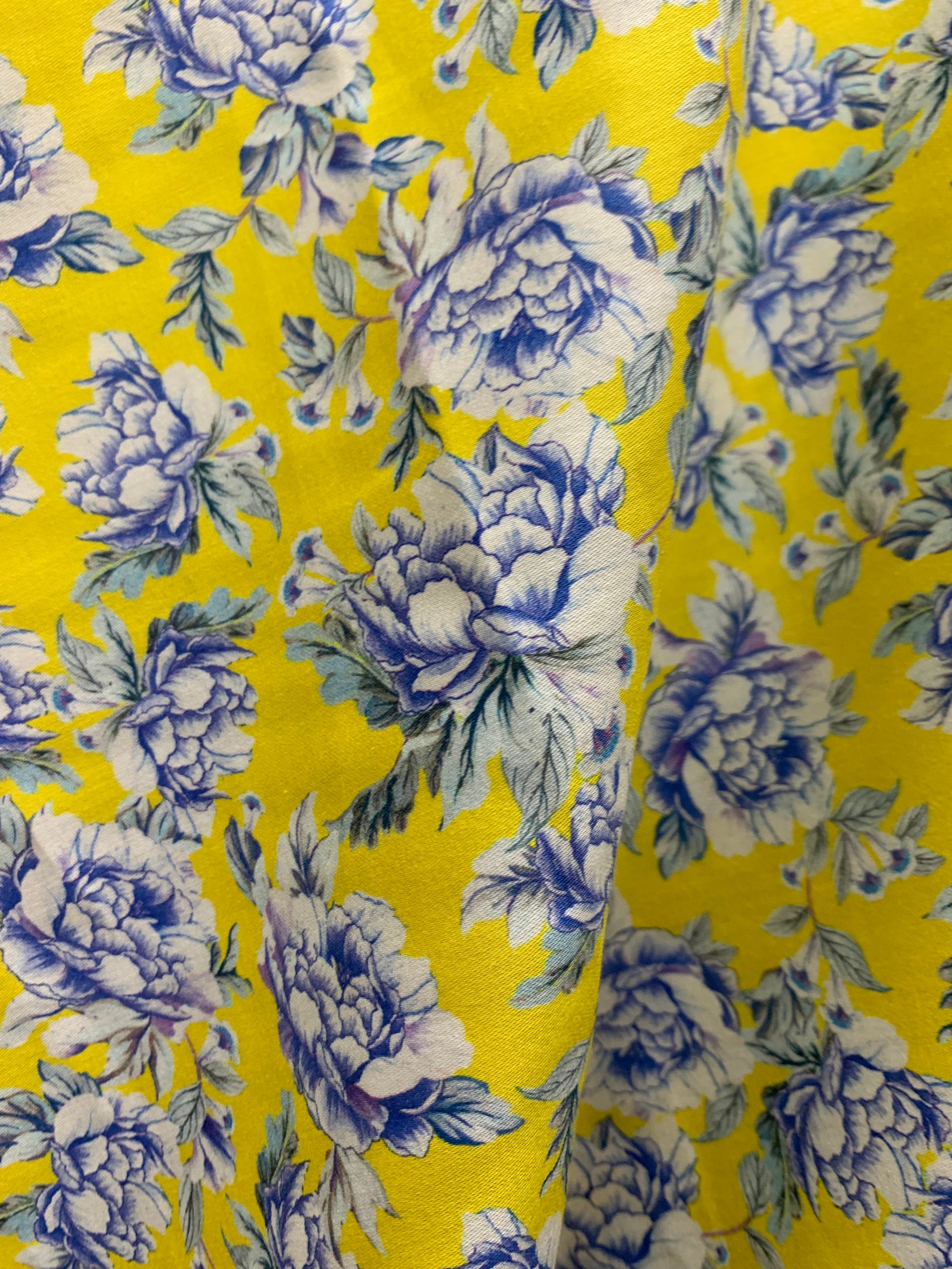 cotton lawn fabric with yellow and  blue/white flowers on a background of yellow with a measuring tape on the bottom