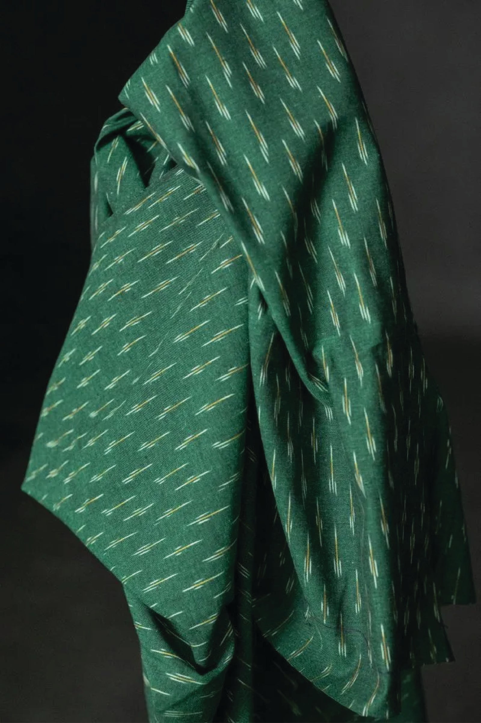 A stunning chequered Ikat weave with ochre and white dashes on a background of dark emerald green.