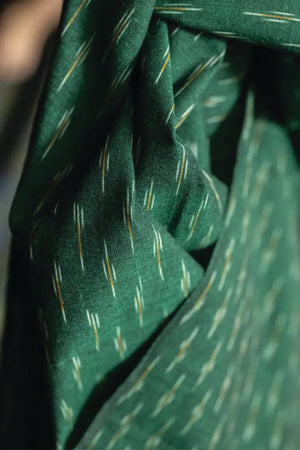 A stunning chequered Ikat weave with ochre and white dashes on a background of dark emerald green.