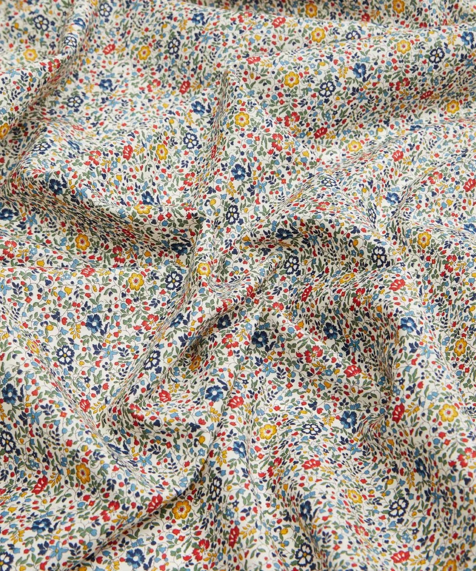 This draped vibrant fabric has a beautiful vintage ditsy floral print of blue, reds, greens, and yellows.