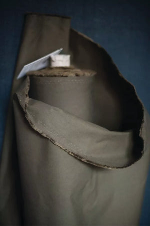 Close-up of a roll of khaki dry oilskin fabric with a dark blue background.