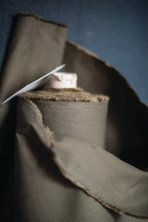 Close-up of a roll of khaki dry oilskin fabric with a dark blue background.