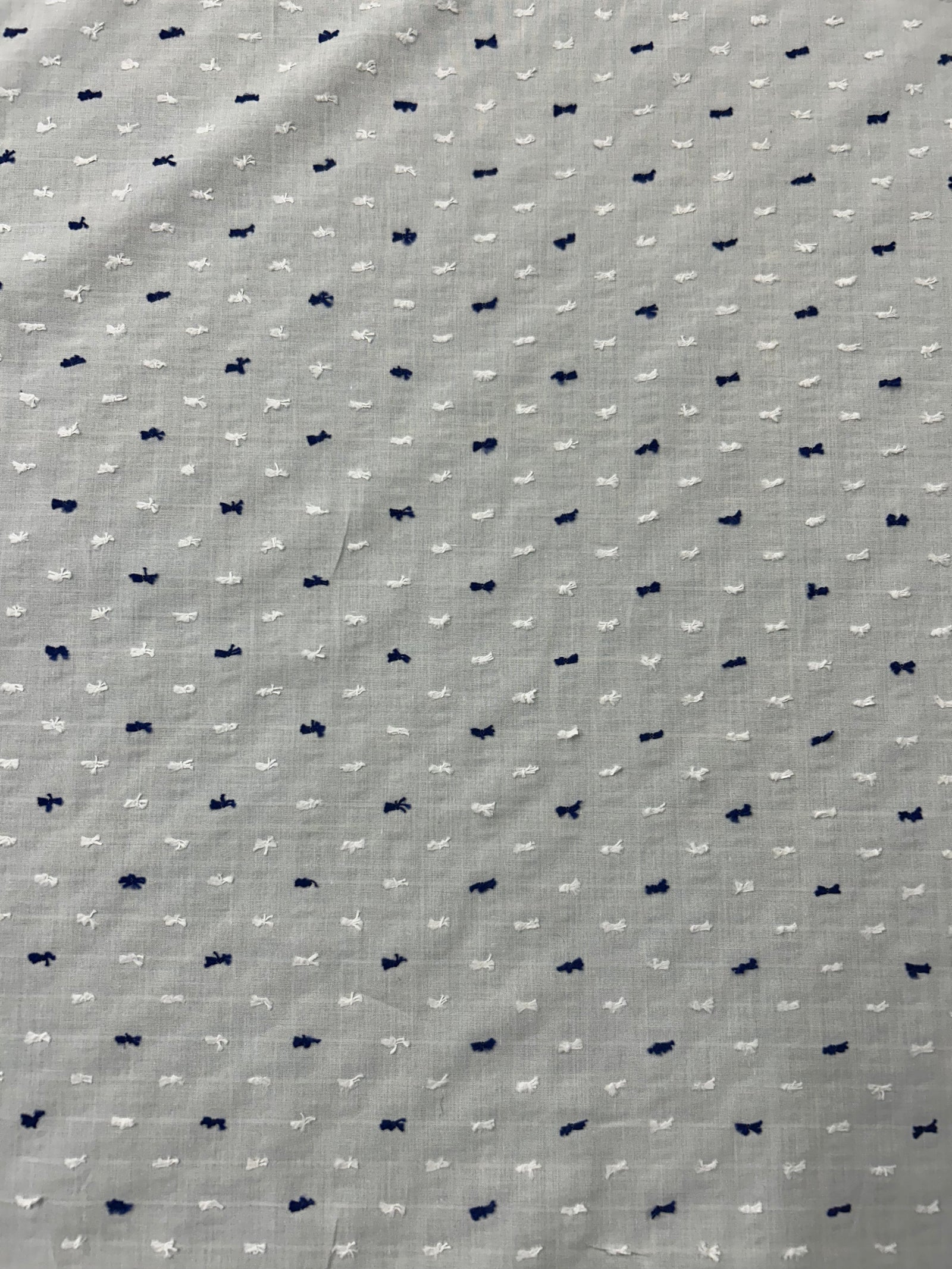 Italian cotton fil coupé fabric features a subtle jacquard-woven Swiss Dot pattern in white and navy on a white background.