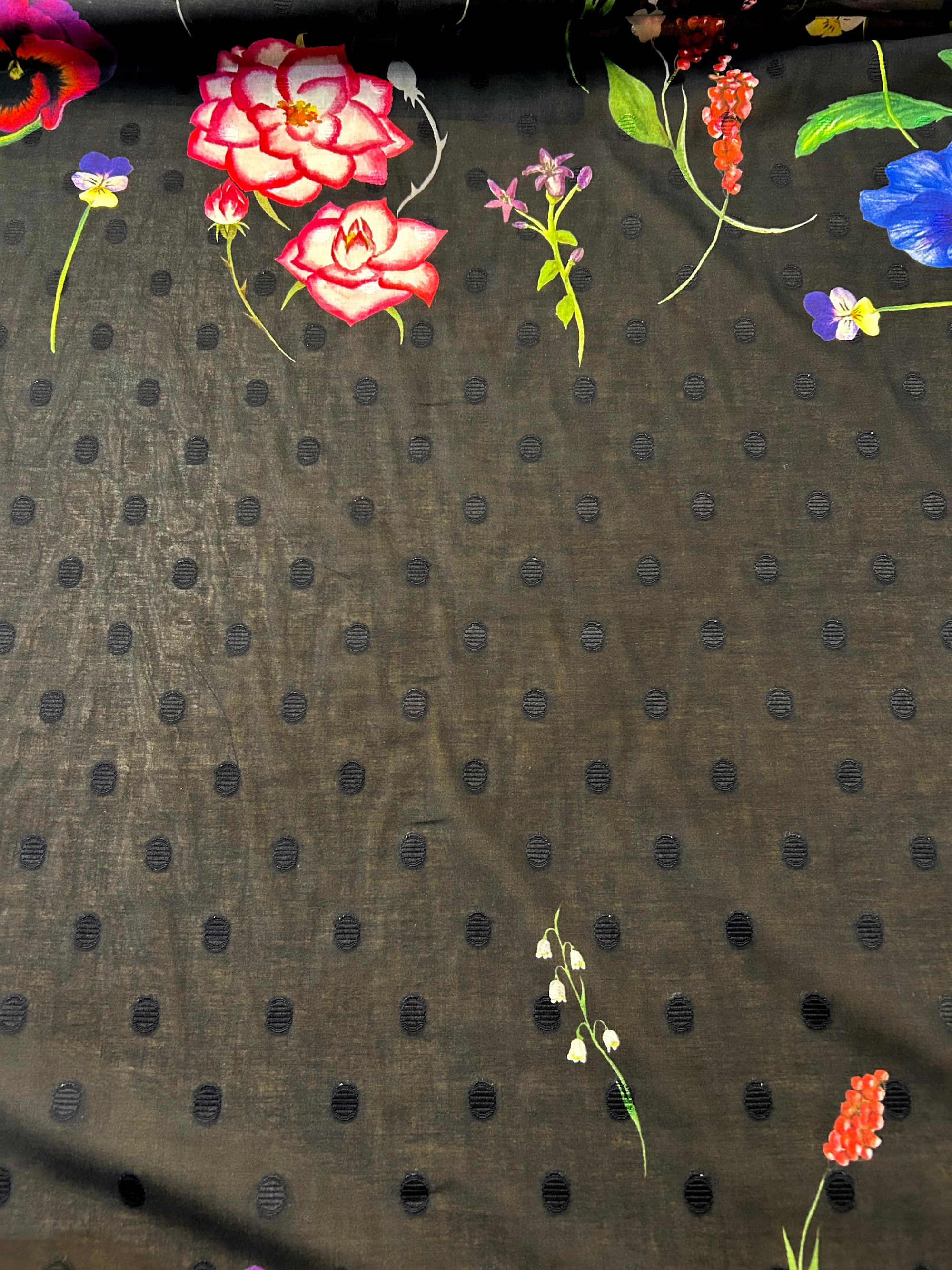 Floral pattern with pink roses and colorful flowers on a black polka dot background