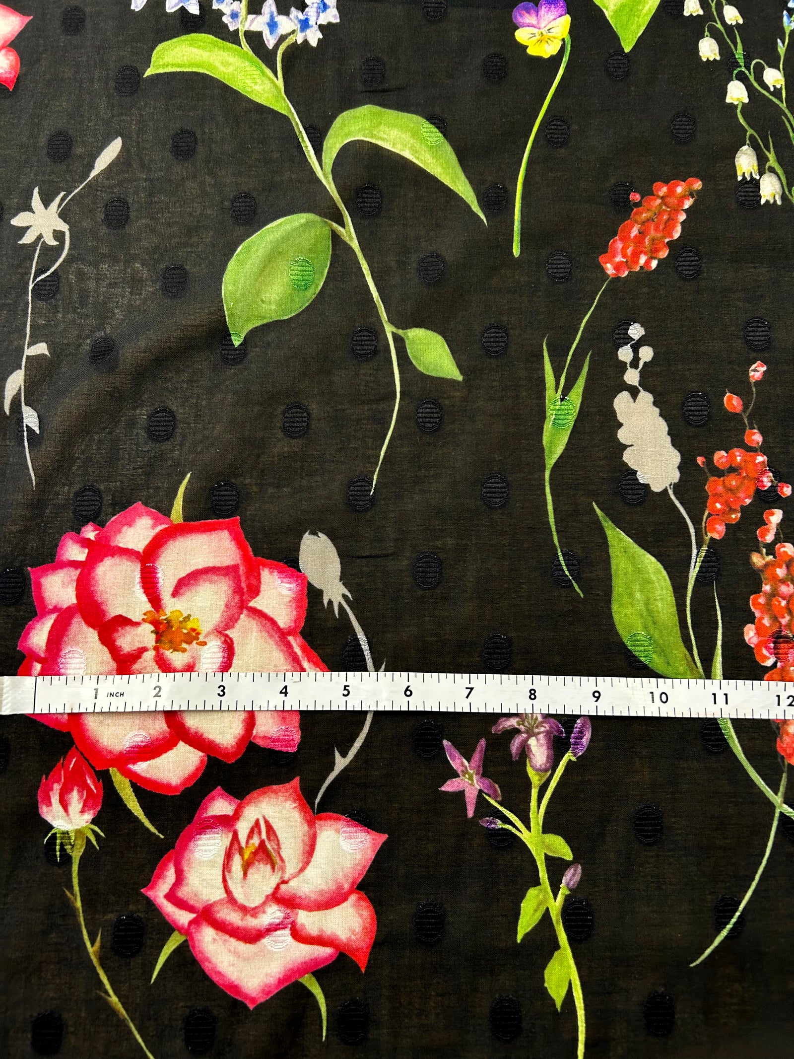 Floral pattern with pink roses and colorful flowers on a black polka dot background